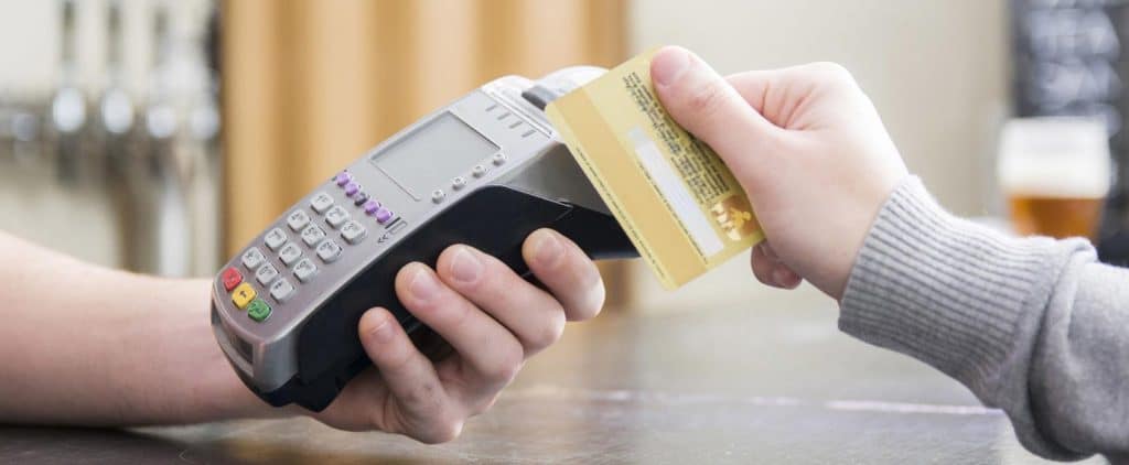 A guy hands over a credit card to a store clerk.